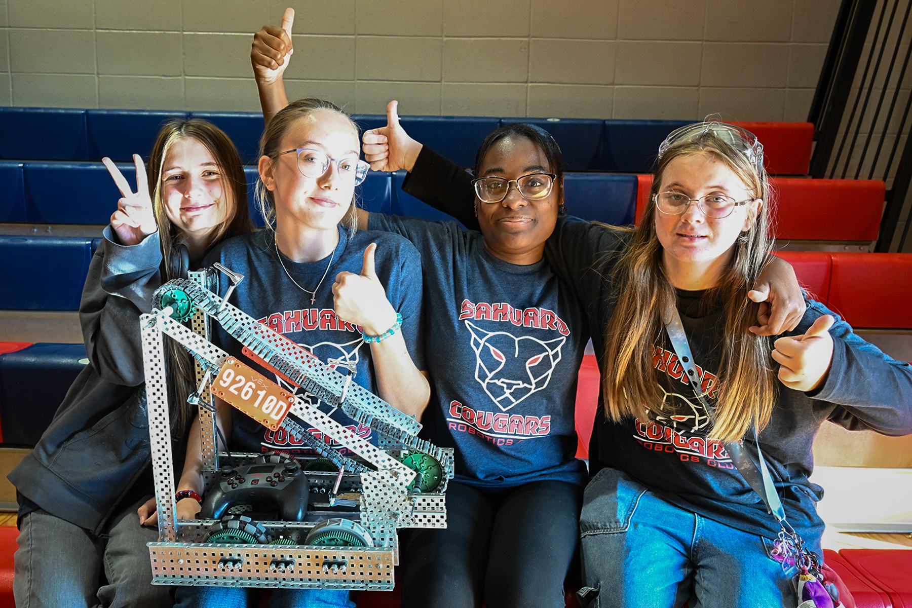 A group of four girls smile with their robot