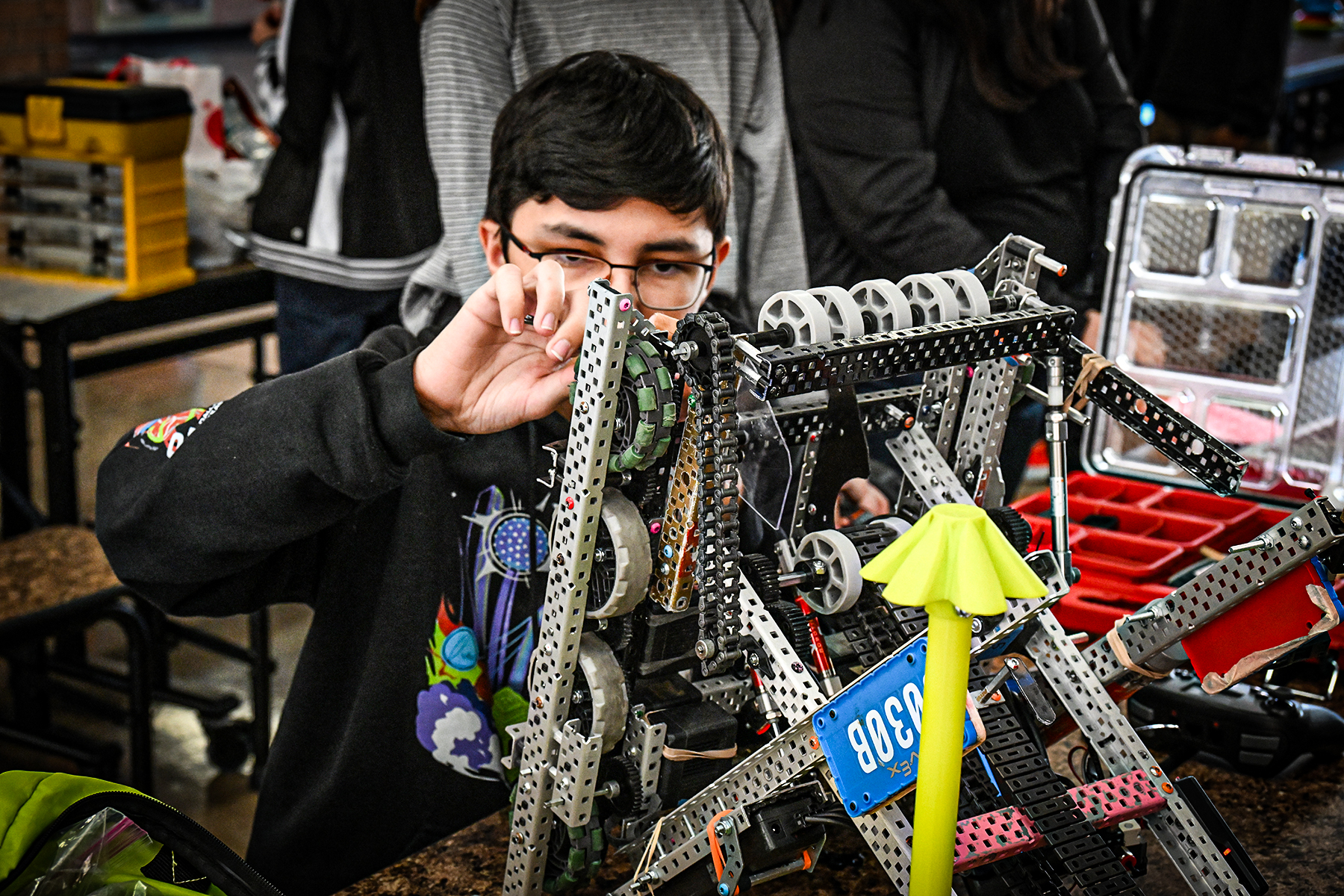 A boy in glasses works on his team's robot