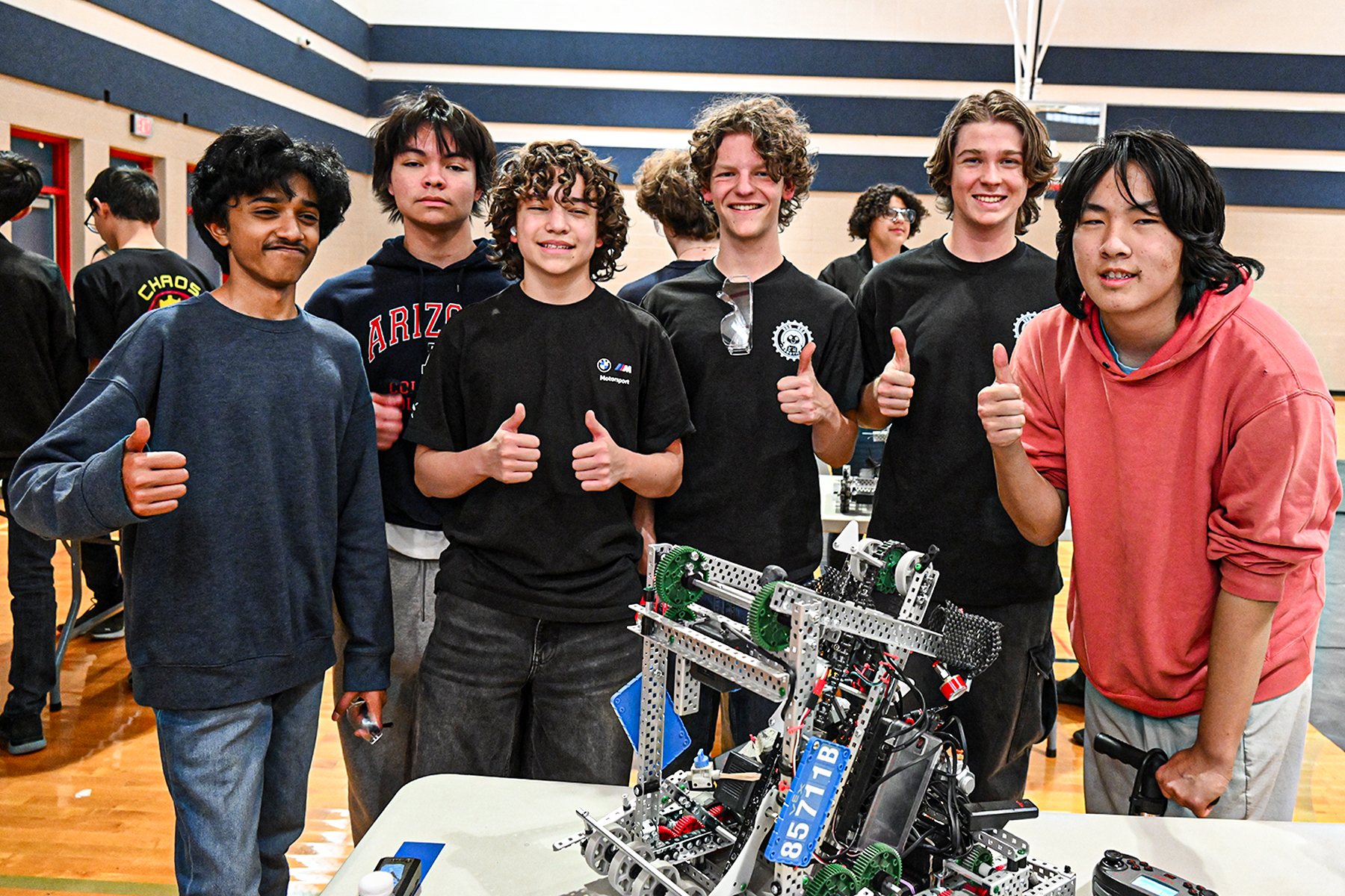 A group of six boys give thumbs up with their robot