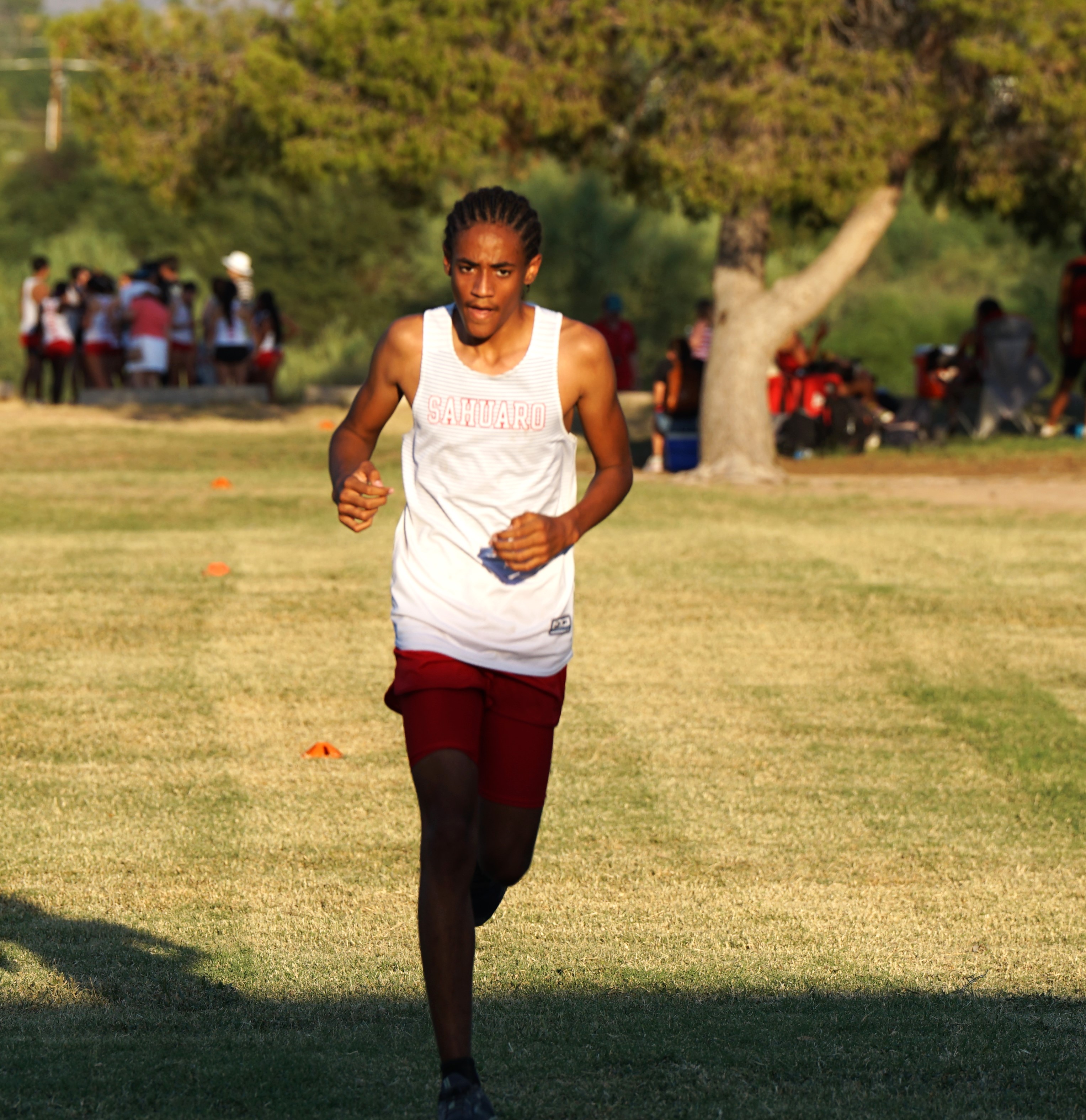 A Sahuaro cross country athlete runs across the grassy field