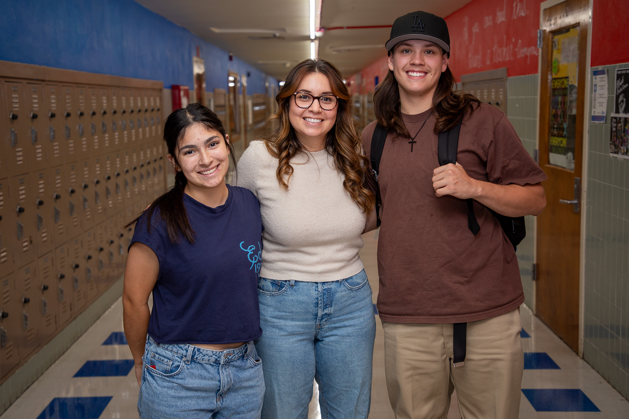 Three students smile together in the hallway