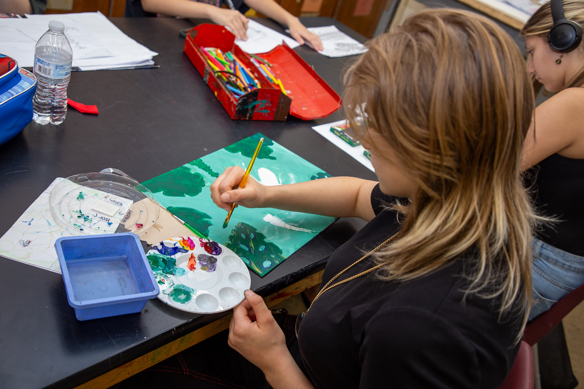 A teen girl paints during art class