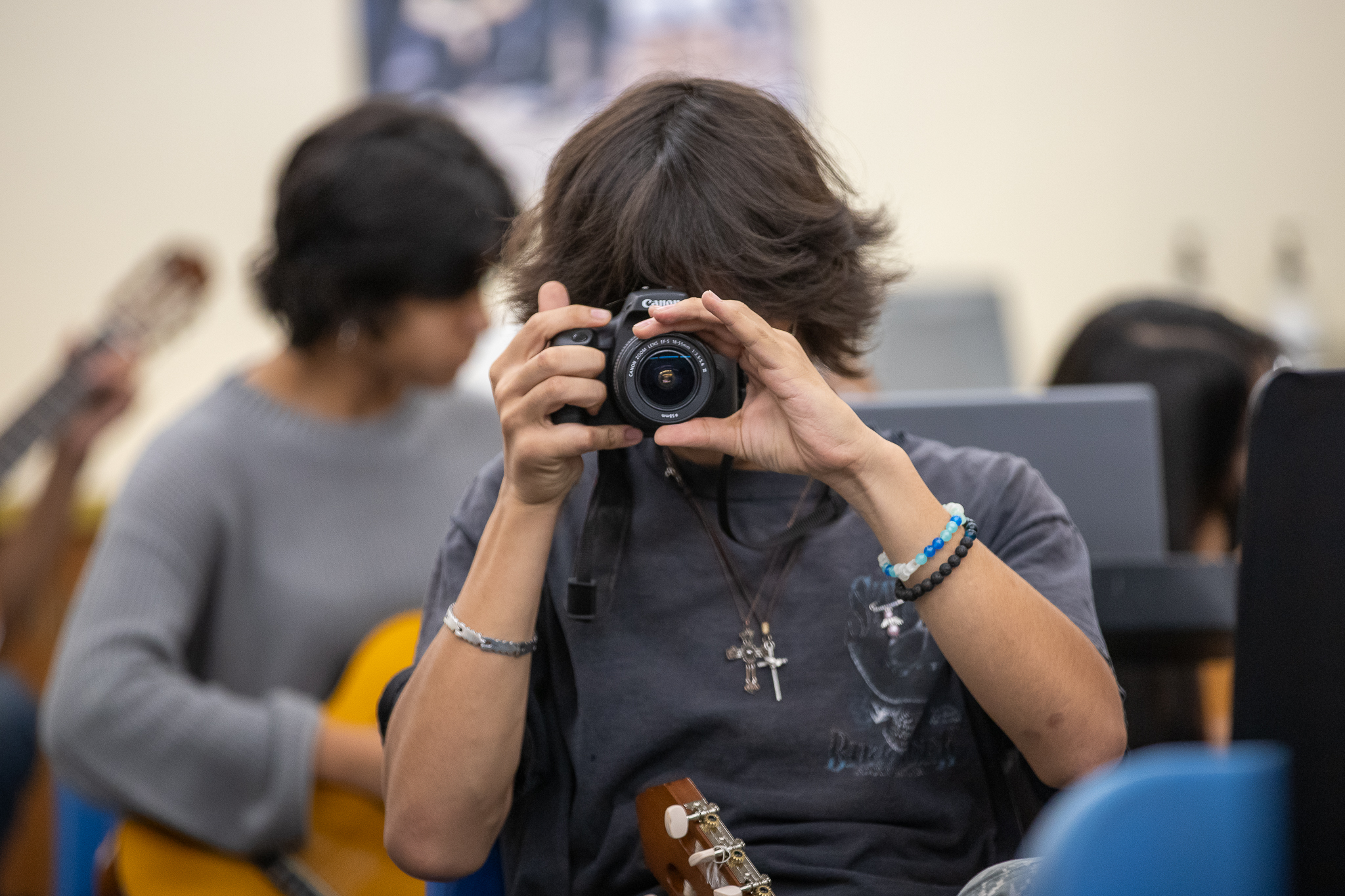 A teen boy uses his camera in a photography class