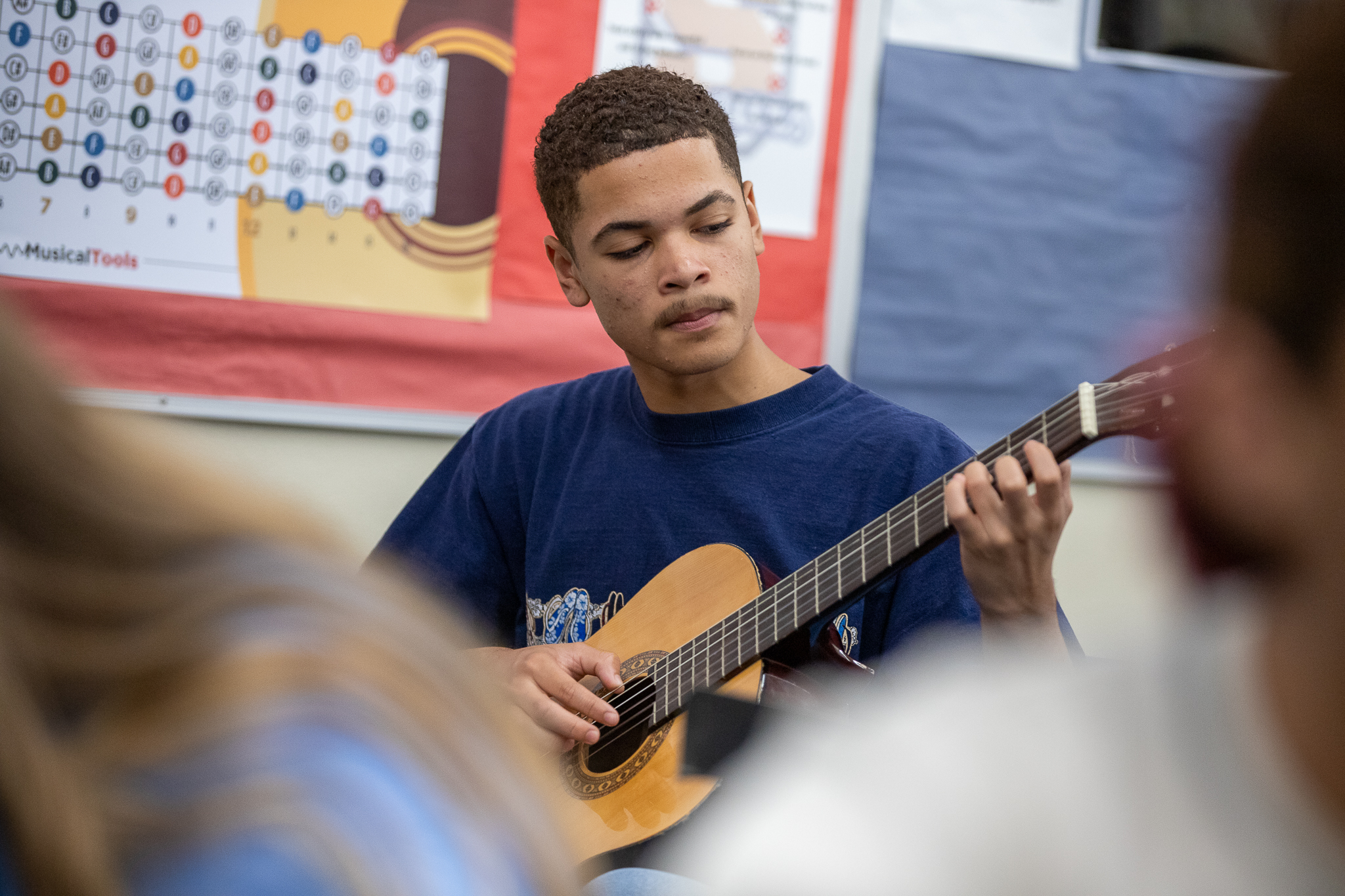 A teen boy focuses while playing guitar