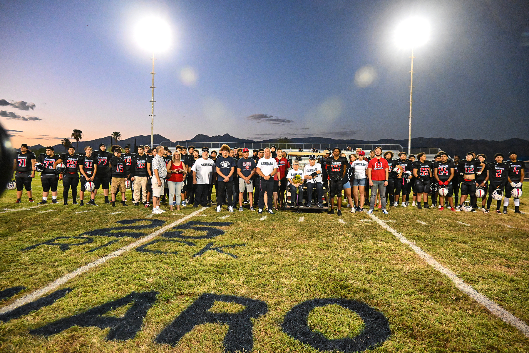 Sahuaro football players and relatives and friends of Rick Botkin gather on the field for the memorial game