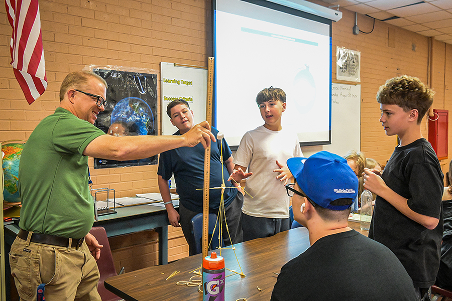 A teacher shows his students how to build a spaghetti tower
