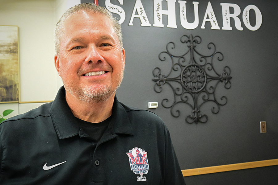 A man smiles next to a sign reading Sahuaro