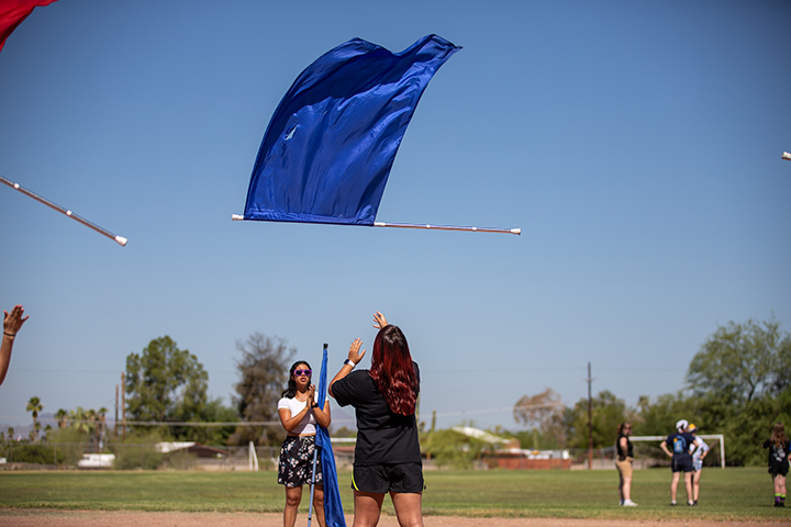 A girl tosses a blue flag in the air