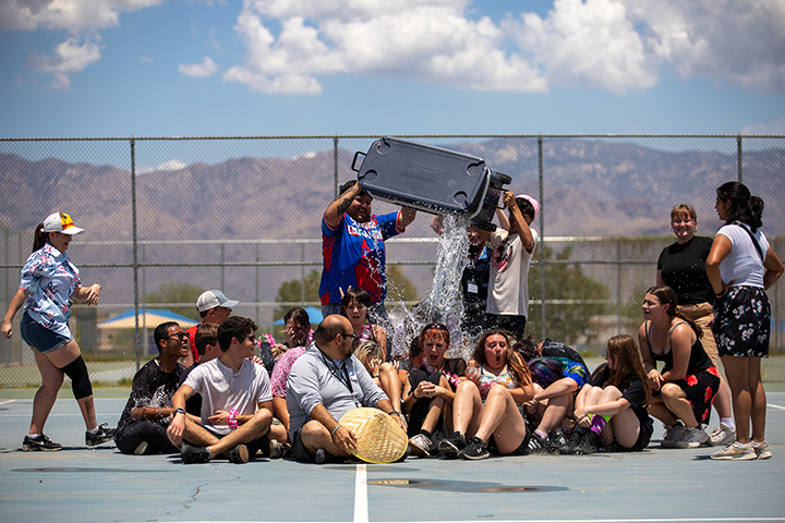 Three students dump a cooler full of water on their bandmates