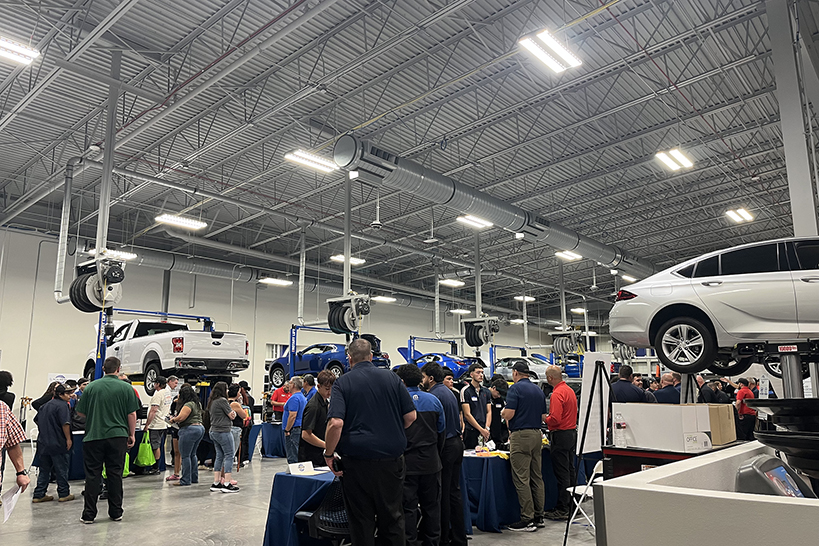 Students look at vehicles up on lifts