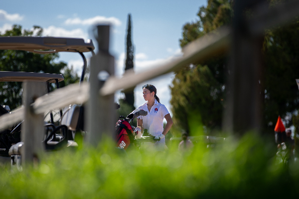 A teen girl in the distance stands on the greens of the golf course