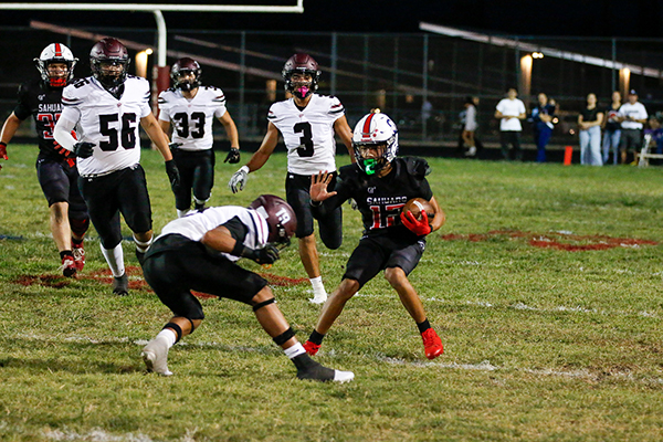 A Sahuaro football player holds off his opponents as he runs with the ball
