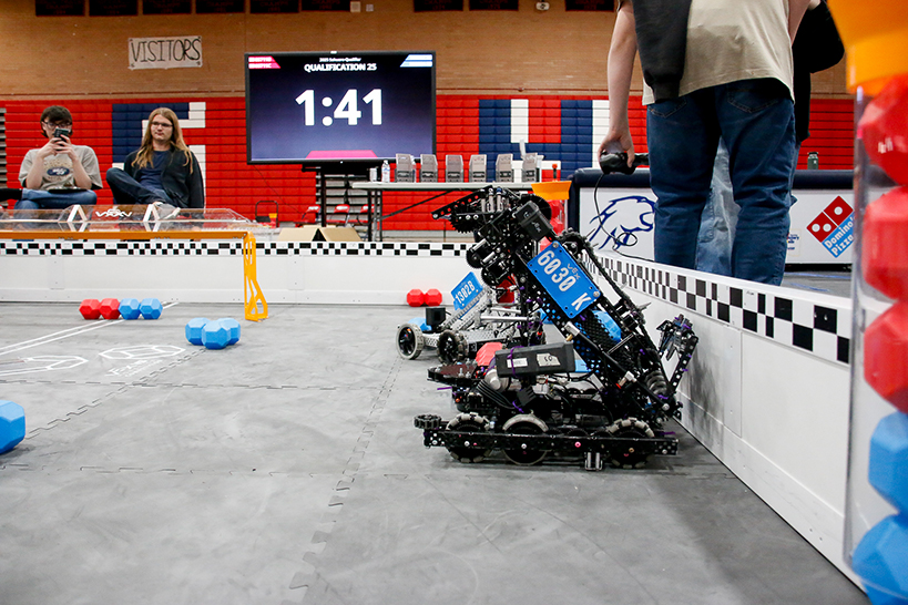 Robots inside the corral, with students sitting outside it watching