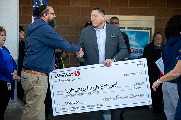 Sahuaro's principal shakes hands with a representative from the Safeway Foundation as he accepts a giant check on the school's behalf