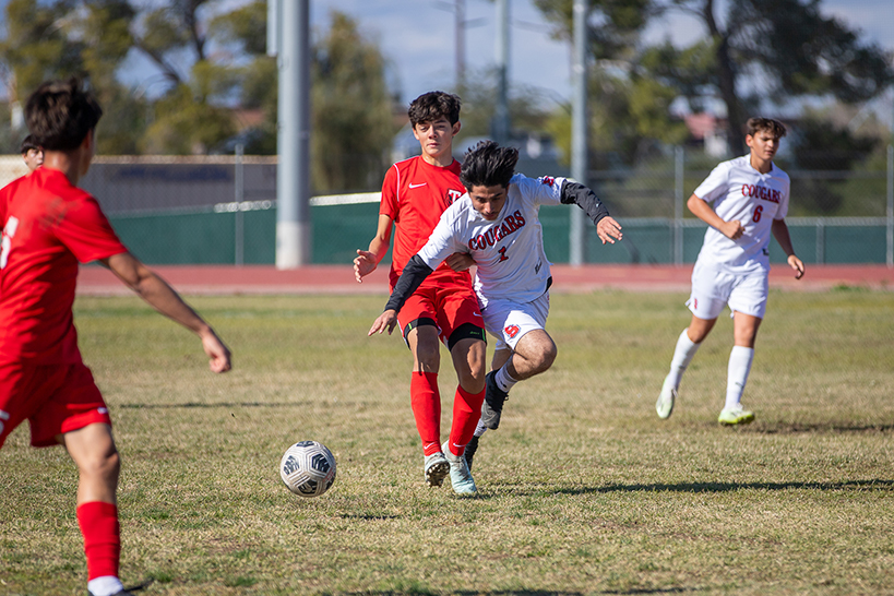 A Sahuaro player dives in front of a Tucson High opponent to get the soccer ball