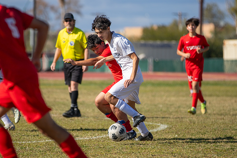 A Sahuaro player tries to keep the soccer ball away from his Tucson High opponent