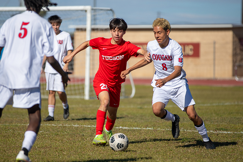 A Sahuaro player pushes past his Tucson High opponent who has the soccer ball