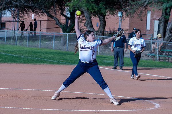 A girl swings her arm to pitch the softball