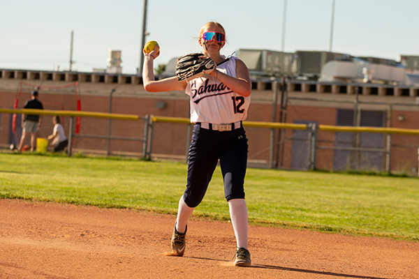 A girl tosses the softball to a teammate