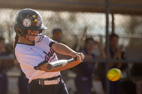 A girl swings the bat at the softball